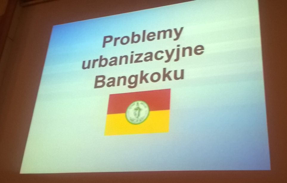 Tablica, na której wyswietla się tytuł wykładu "Problemy urbanizacyjne Bankoku"