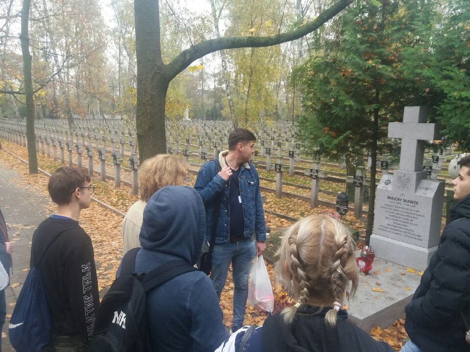 Grupa uczniów stoi przed grobem Walerego Sławka