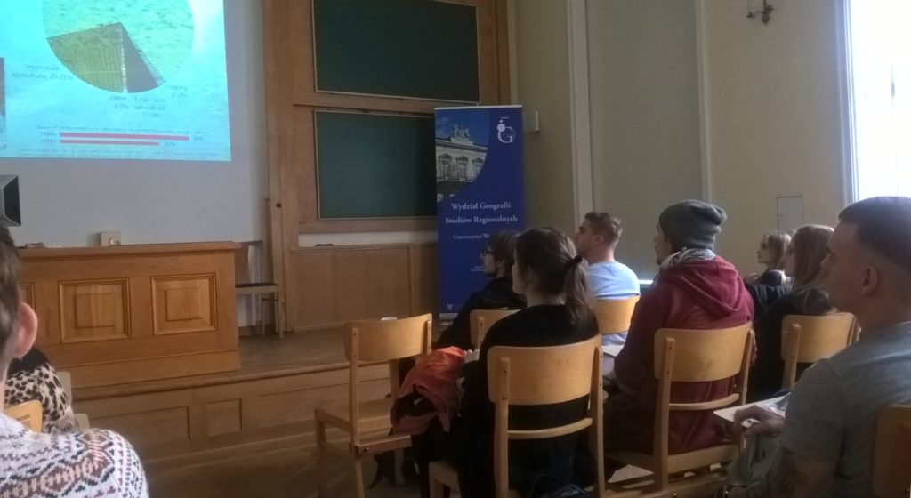 Uczniowie oglądają prezentacje i słuchająwykładowcy Uniwersytetu Warszawskiego.