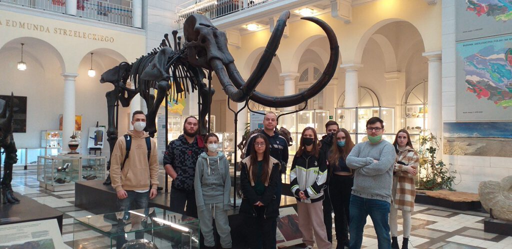 Grupa słuchaczy stoi przy szkielecie mamuta