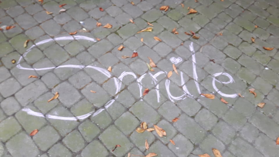 Napis białą kredą na chodniku "Smile"