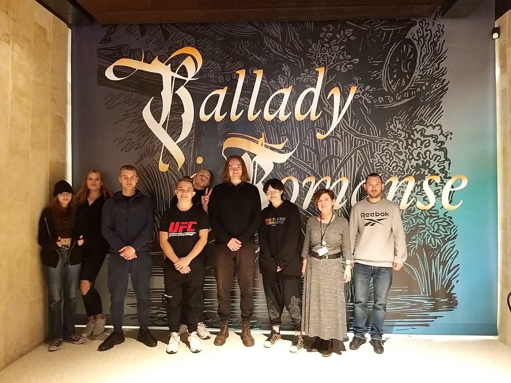 Grupa uczniów stoi na tle muralu z napisem Ballady i romanse
