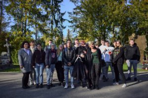 grupa uczniów stoi przed wejściem na cmentarz