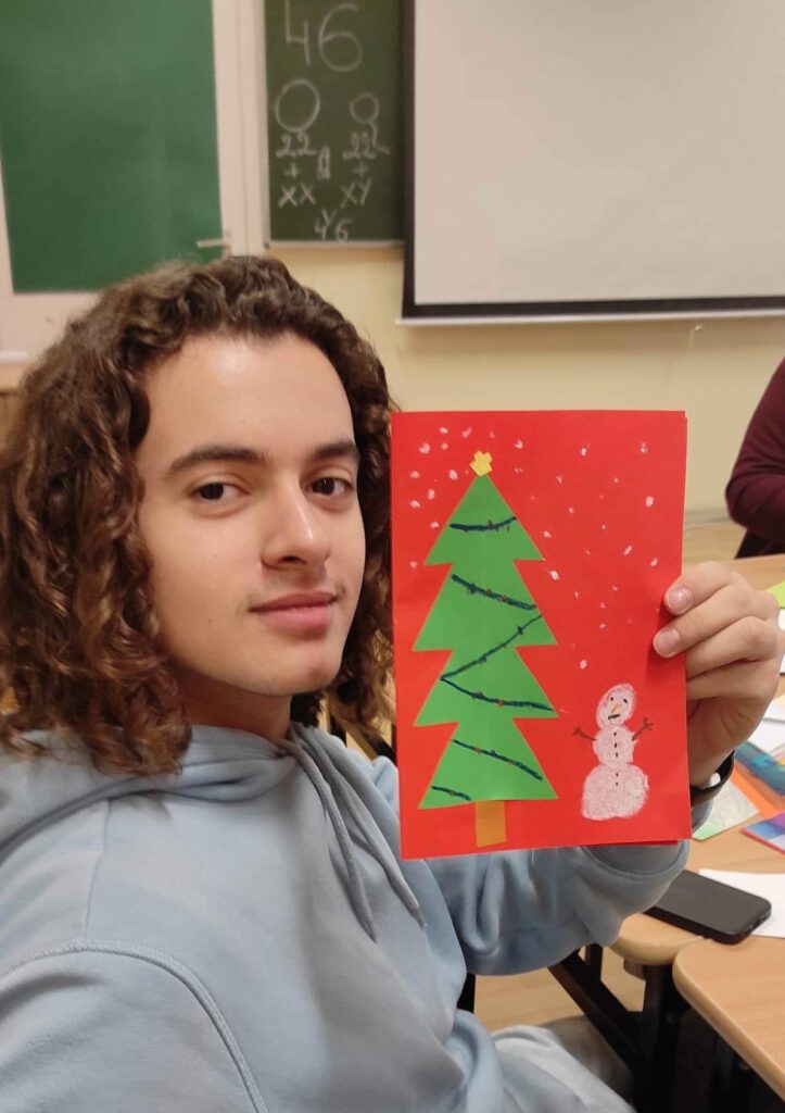 Uczeń trzyma w ręku kartkę świąteczną