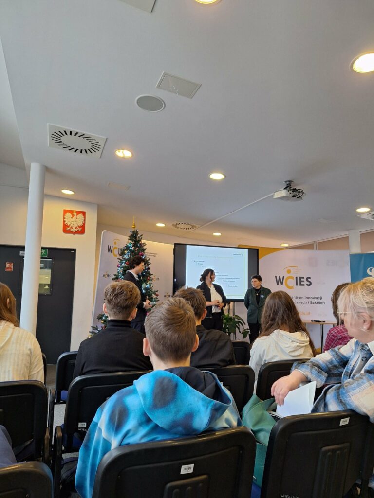 Zdjęcie z widowni przedstawiające trzy osoby biorące udział w debacie.